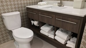 Une salle de bain comprenant des toilettes, un lavabo et un meuble-lavabo avec des serviettes.