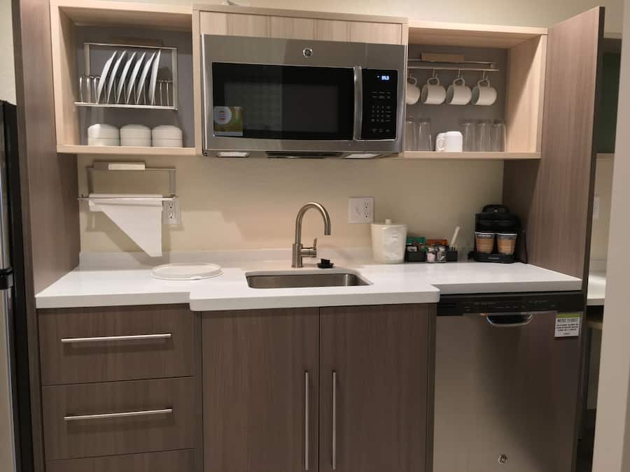 Una cocina moderna con microondas de acero inoxidable, un fregadero y armarios de madera.
