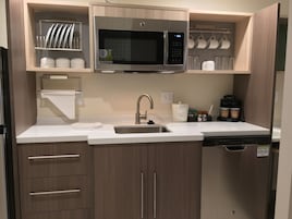 Una cocina moderna con microondas de acero inoxidable, un fregadero y armarios de madera.