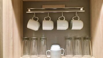 Un gabinete de madera con un estante que contiene tazas blancas y vasos de vidrio.