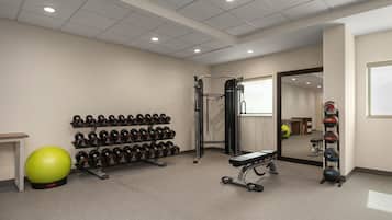 A gym with weightlifting equipment, a mirrored wall, and a green exercise ball.