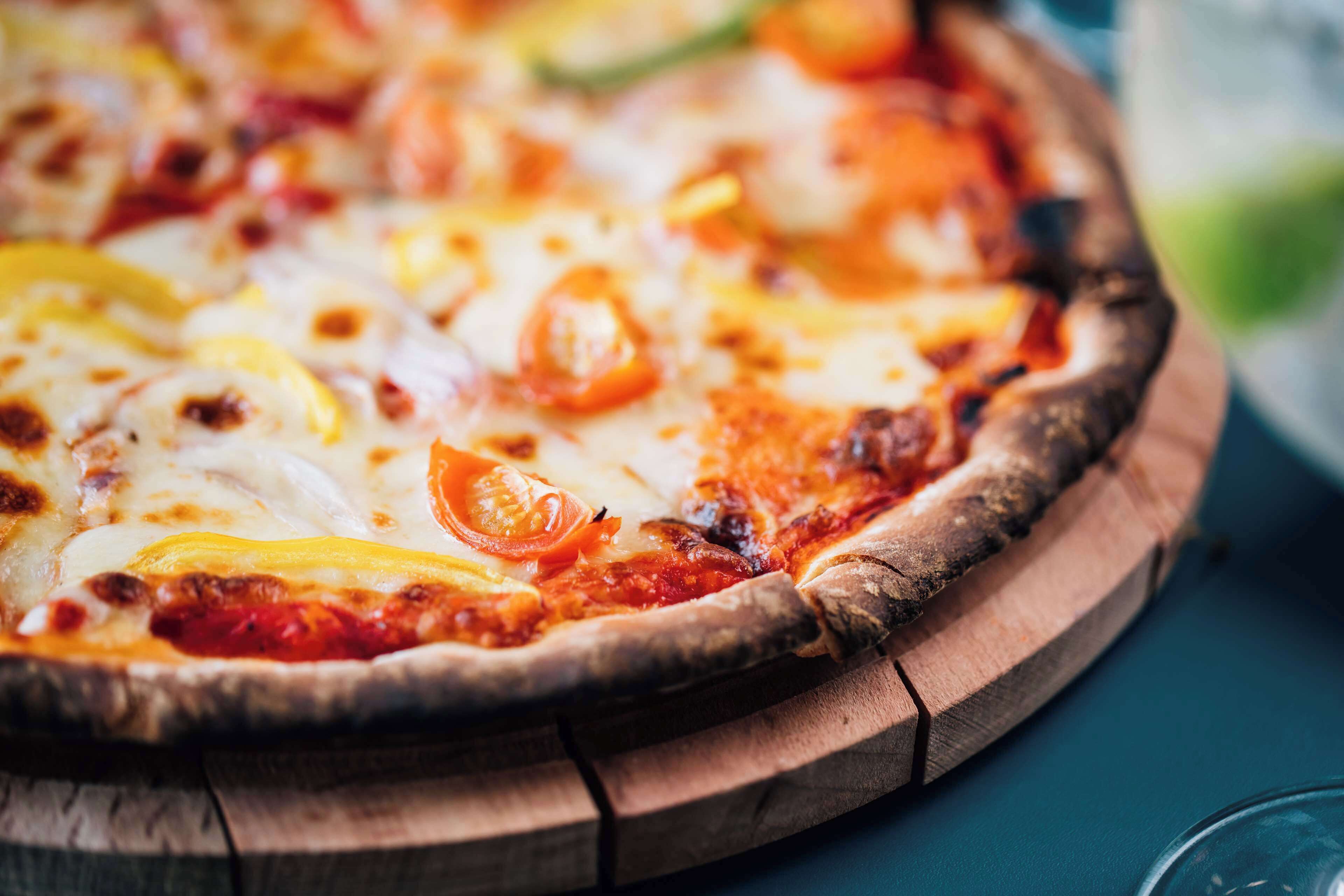 Une pizza servie sur une planche en bois.