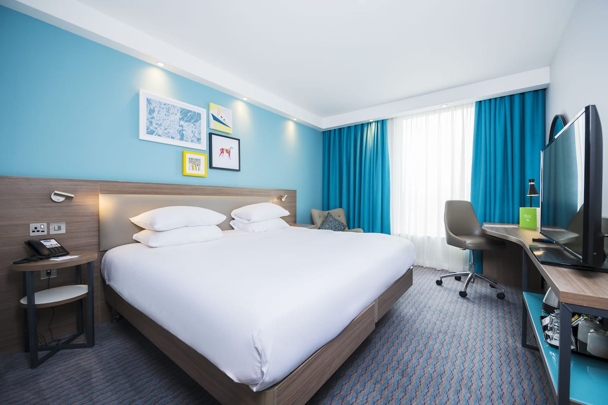 Une chambre d’hôtel avec un grand lit, un bureau avec un ordinateur, une chaise et un téléviseur.