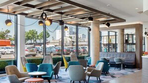 A modern interior with seating areas, large windows, and a view of the street.
