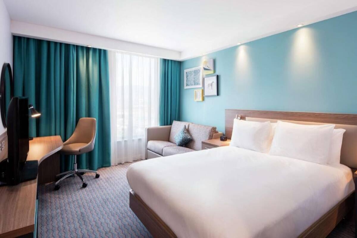 Une chambre d’hôtel avec un grand lit, un bureau avec une chaise, un canapé et un téléviseur.