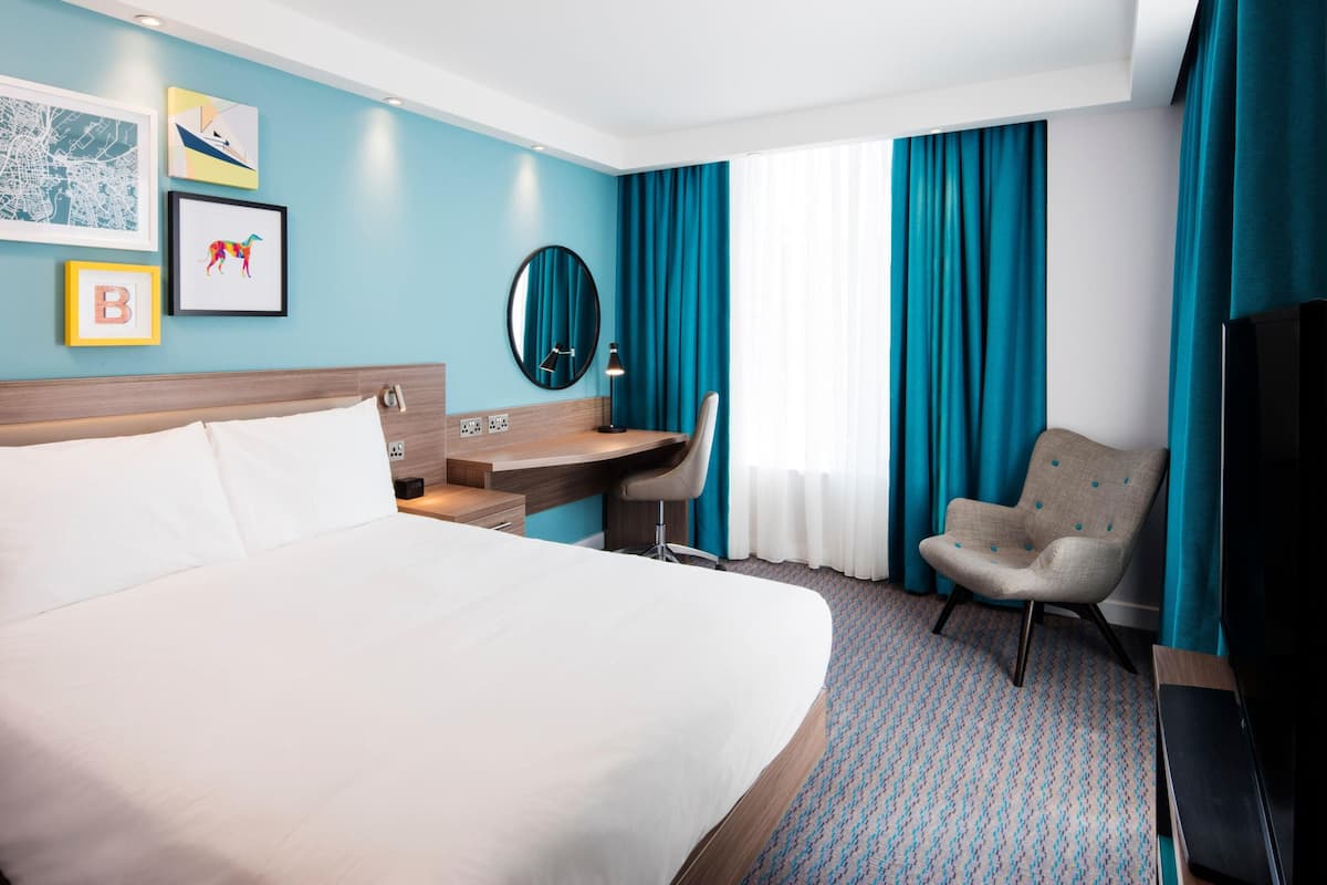 Une chambre d’hôtel avec un lit, un bureau, une chaise et un téléviseur.