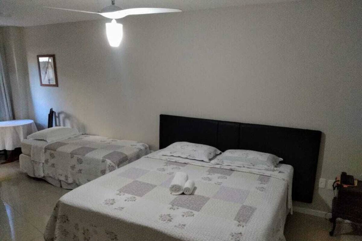 A hotel room with two beds, a small table, a chair, and a ceiling fan.