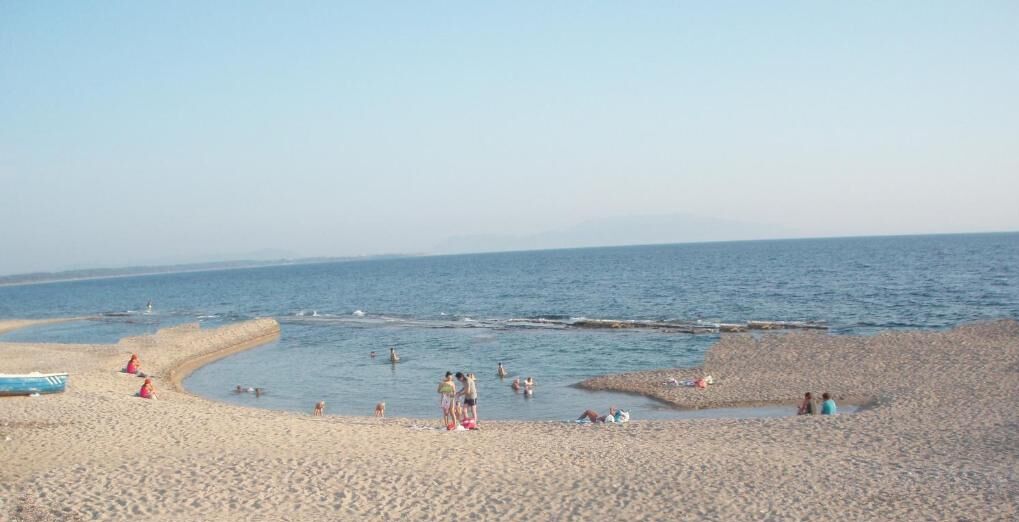 A beach with people swimming and relaxing.