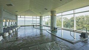 Ein großzügiger Innenpoolbereich mit Steinfußboden, großen Fenstern und mehreren Wasserspielen.