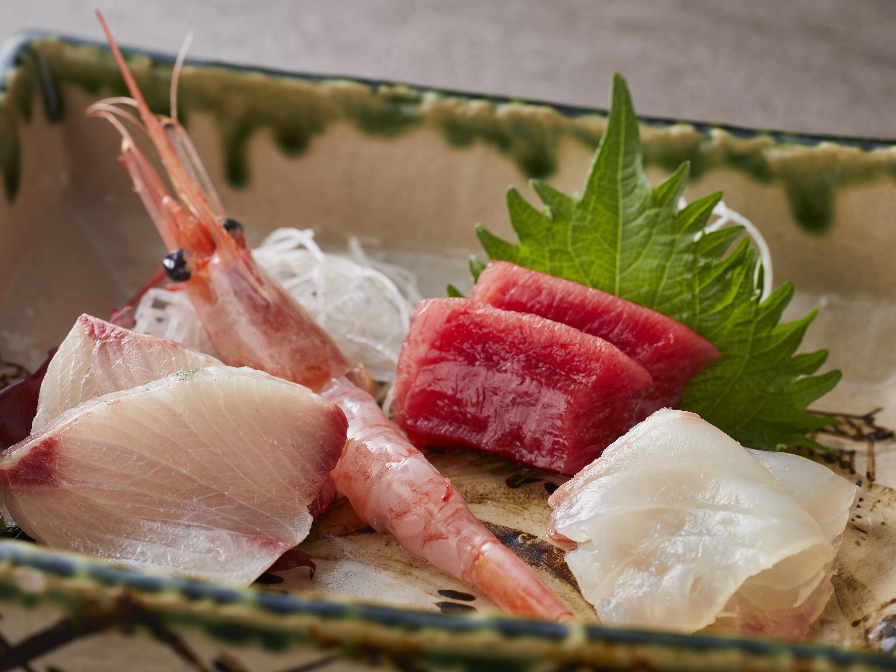 A ceramic dish with raw fish and seafood.