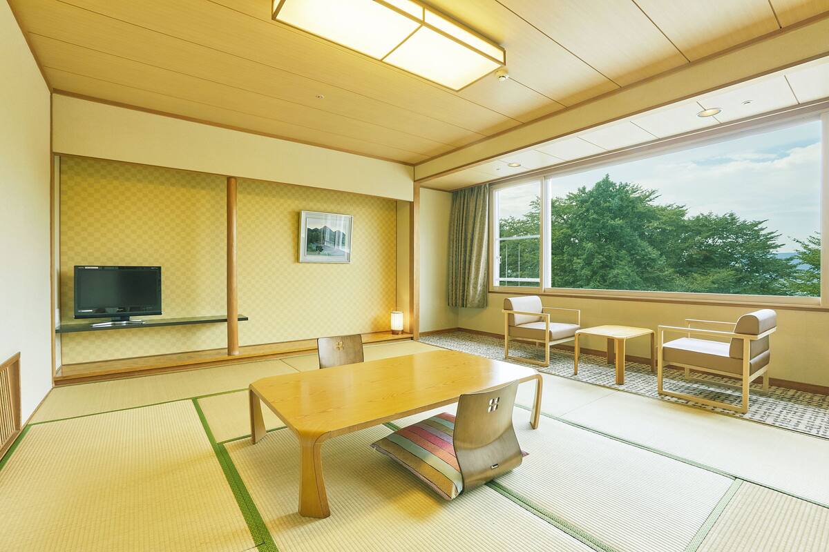 A traditional Japanese-style room with tatami flooring, a low table, and seating.