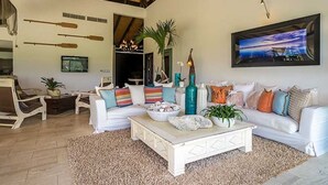 Un salon spacieux avec un canapé blanc, une table basse et un grand tableau accroché au mur.