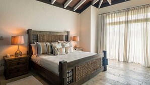 Une chambre à coucher avec un lit en bois, deux tables de chevet et une grande fenêtre avec des rideaux.