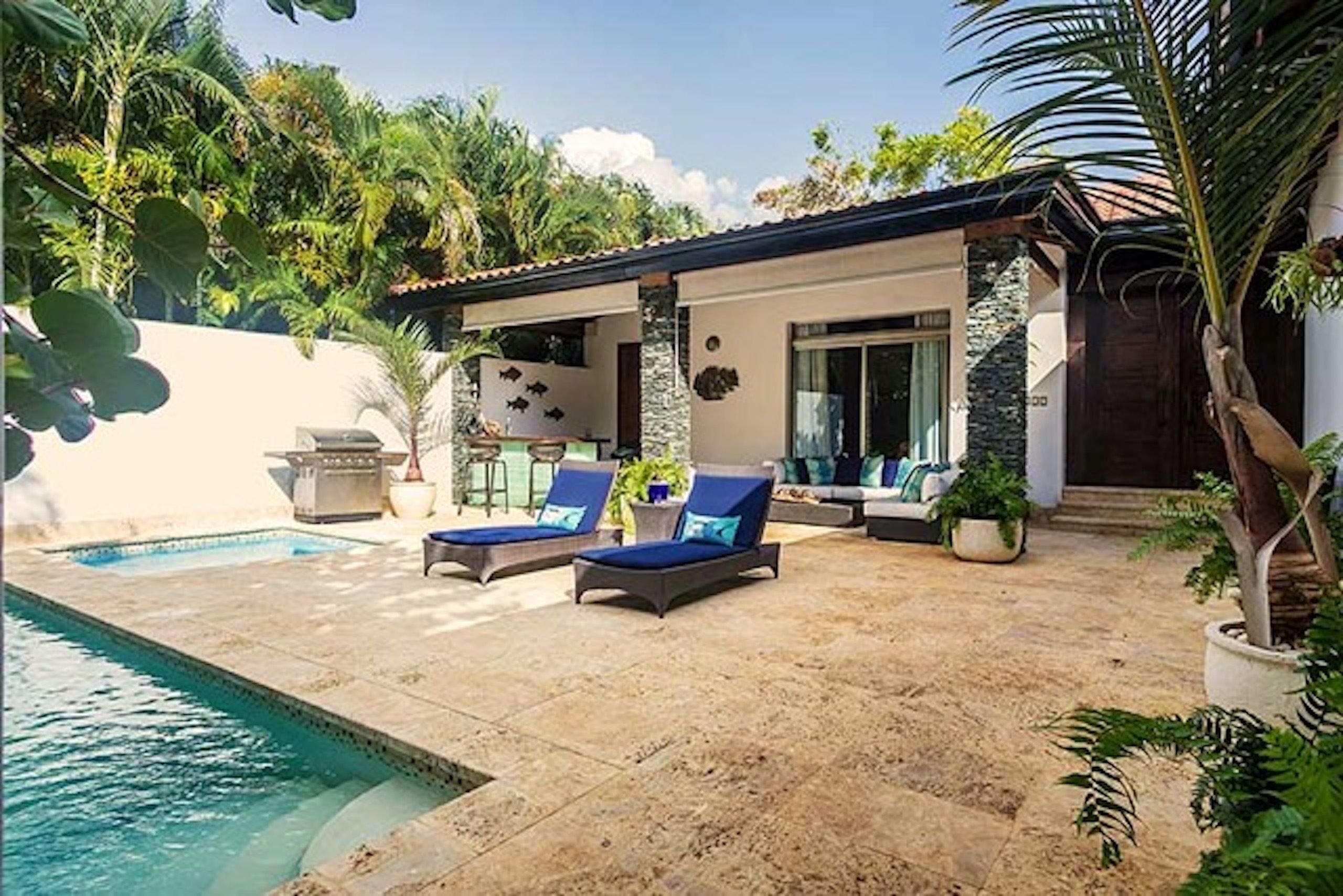 Un área junto a la piscina con sillones de descanso, un pequeño patio y una piscina.