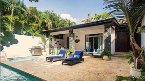 Un espace aménagé au bord de la piscine, avec des chaises longues, une petite terrasse et une piscine.
