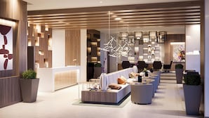 A modern hotel lobby with a reception desk, seating area, and a bar. - AC Hotel by Marriott Santa Marta (Santa Marta)
