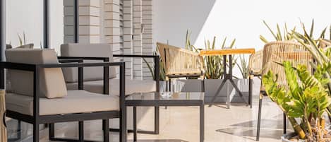 Un área de estar moderna al aire libre con mobiliario contemporáneo y plantas en macetas.