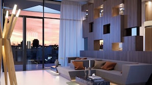 A modern living room with a large sofa, a coffee table, and a city view through floor-to-ceiling windows. - AC Hotel by Marriott Santa Marta (Santa Marta)