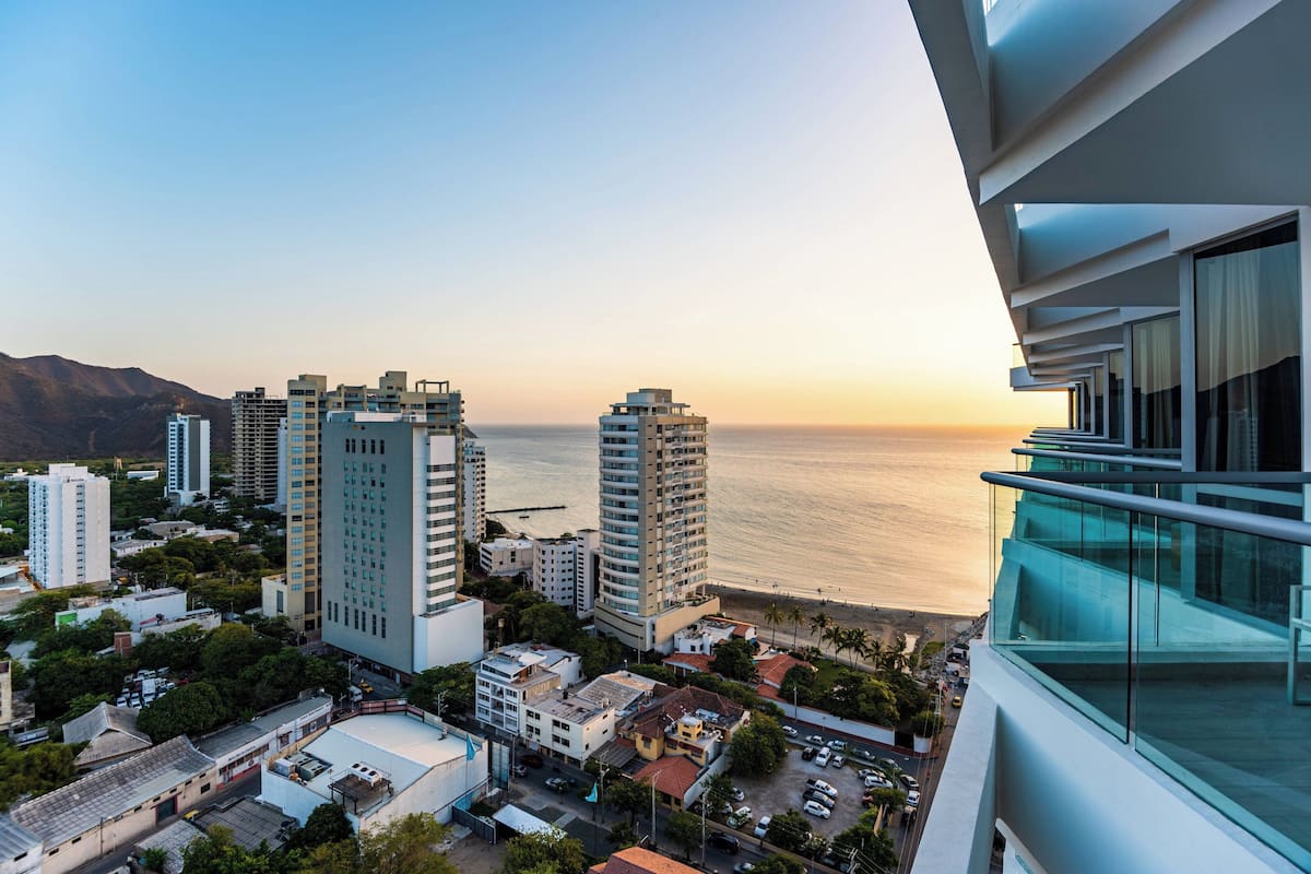 Un edificio de gran altura con varias plantas, vista al mar y un paisaje urbano al fondo.