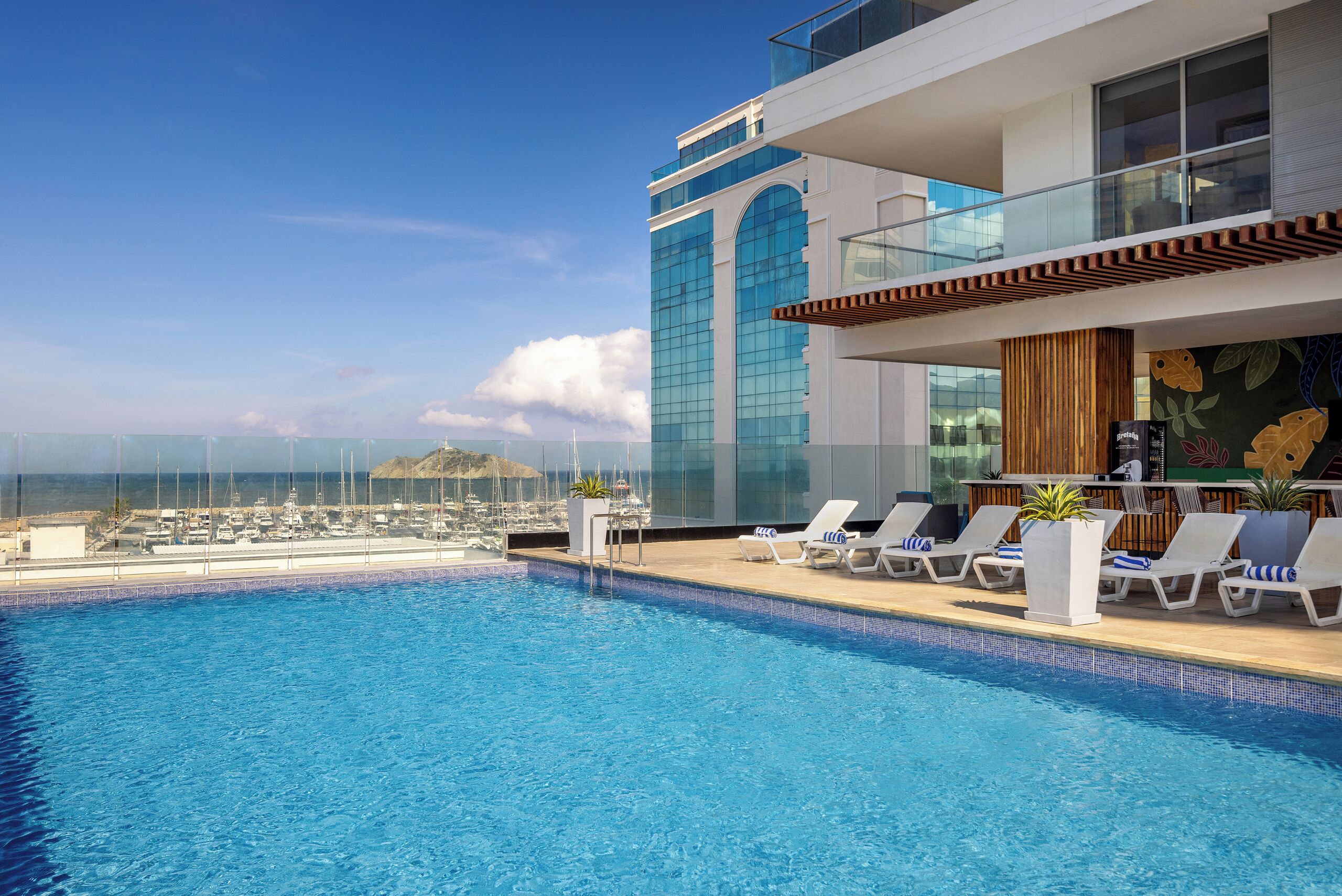 A rooftop pool with lounge chairs and a view of the marina.