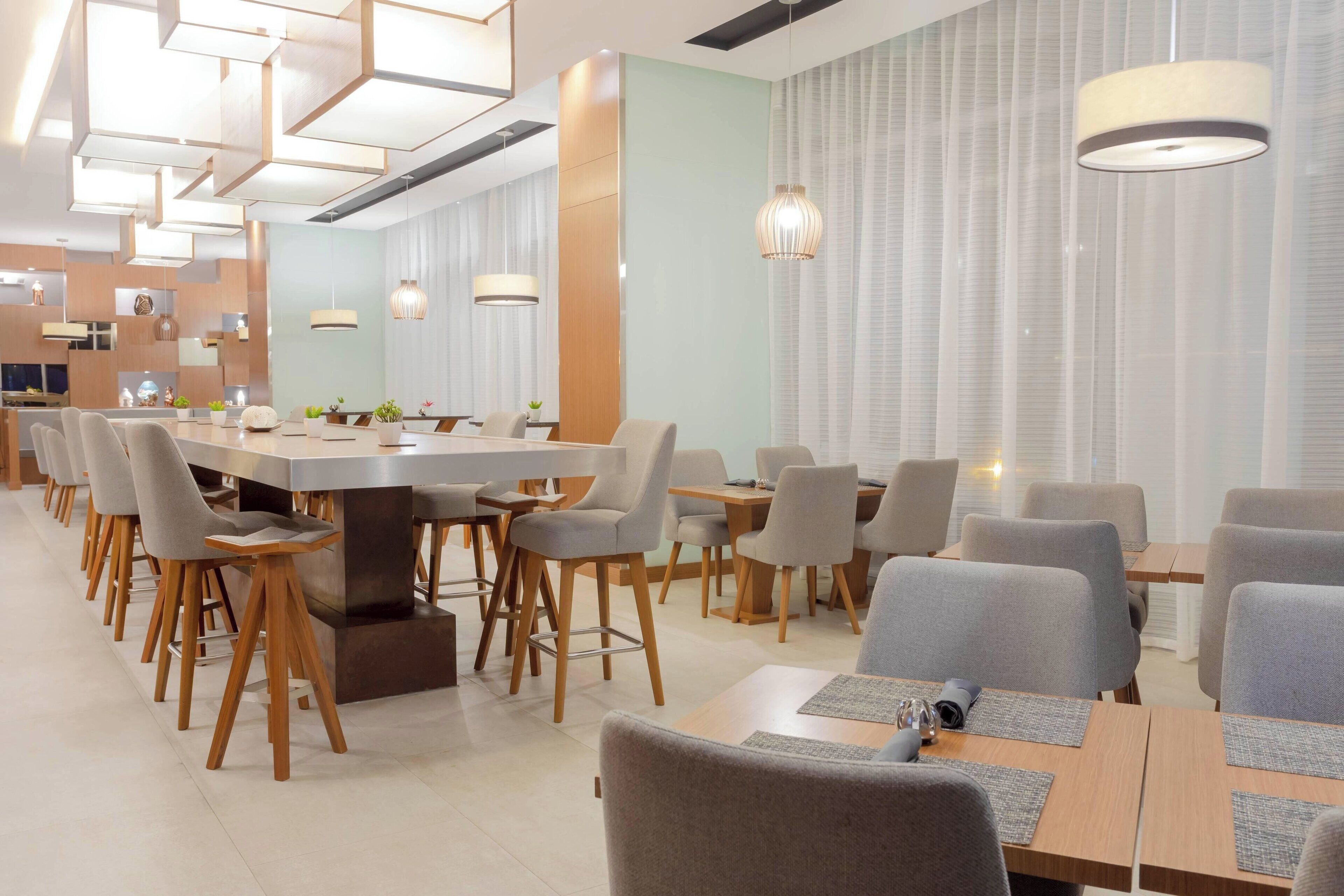 Un comedor moderno con una larga mesa común, mesas individuales y sillas.