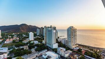 A coastal cityscape with high-rise buildings, a beach, and a mountain in the background.