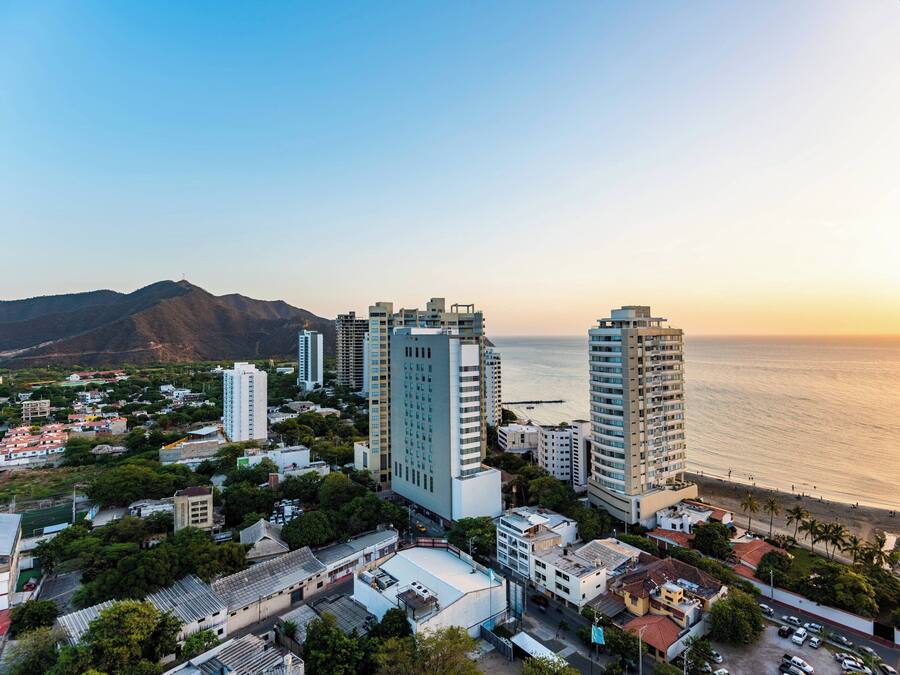 A coastal cityscape with high-rise buildings, a beach, and a mountain in the background.