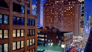 Un paisaje urbano nocturno con edificios altos, algunos con ventanas e iluminación y señalización.