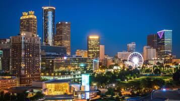 A city skyline at night with illuminated buildings and a Ferris wheel.