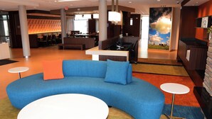 A modern lobby with a blue sofa, a white round table, and a reception desk. - Fairfield Inn & Suites by Marriott Somerset (Somerset)