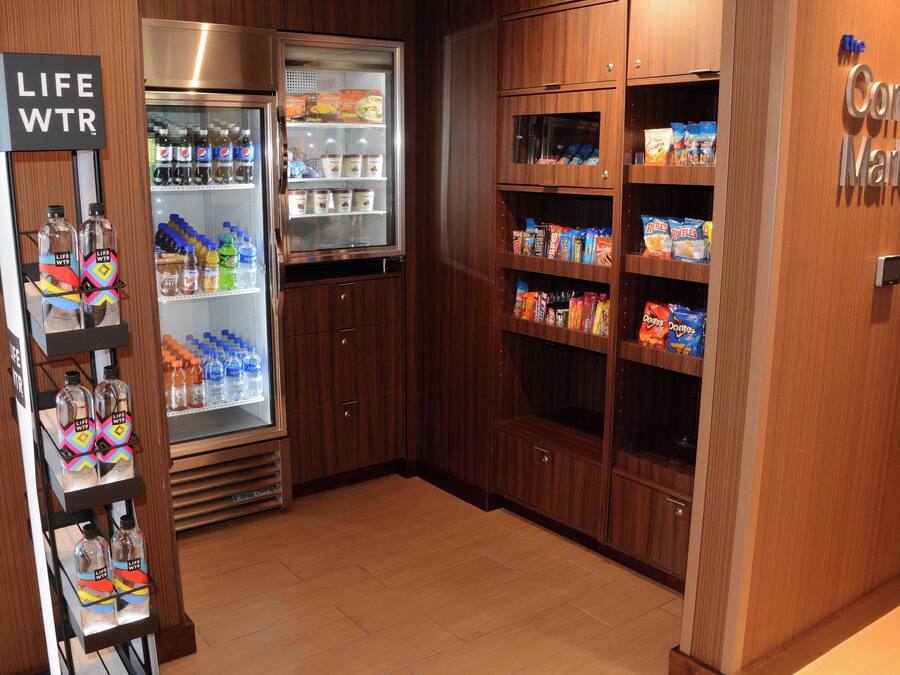 Un angolo della hall di un hotel con una vetrina refrigerata, un distributore automatico e scaffali pieni di snack.