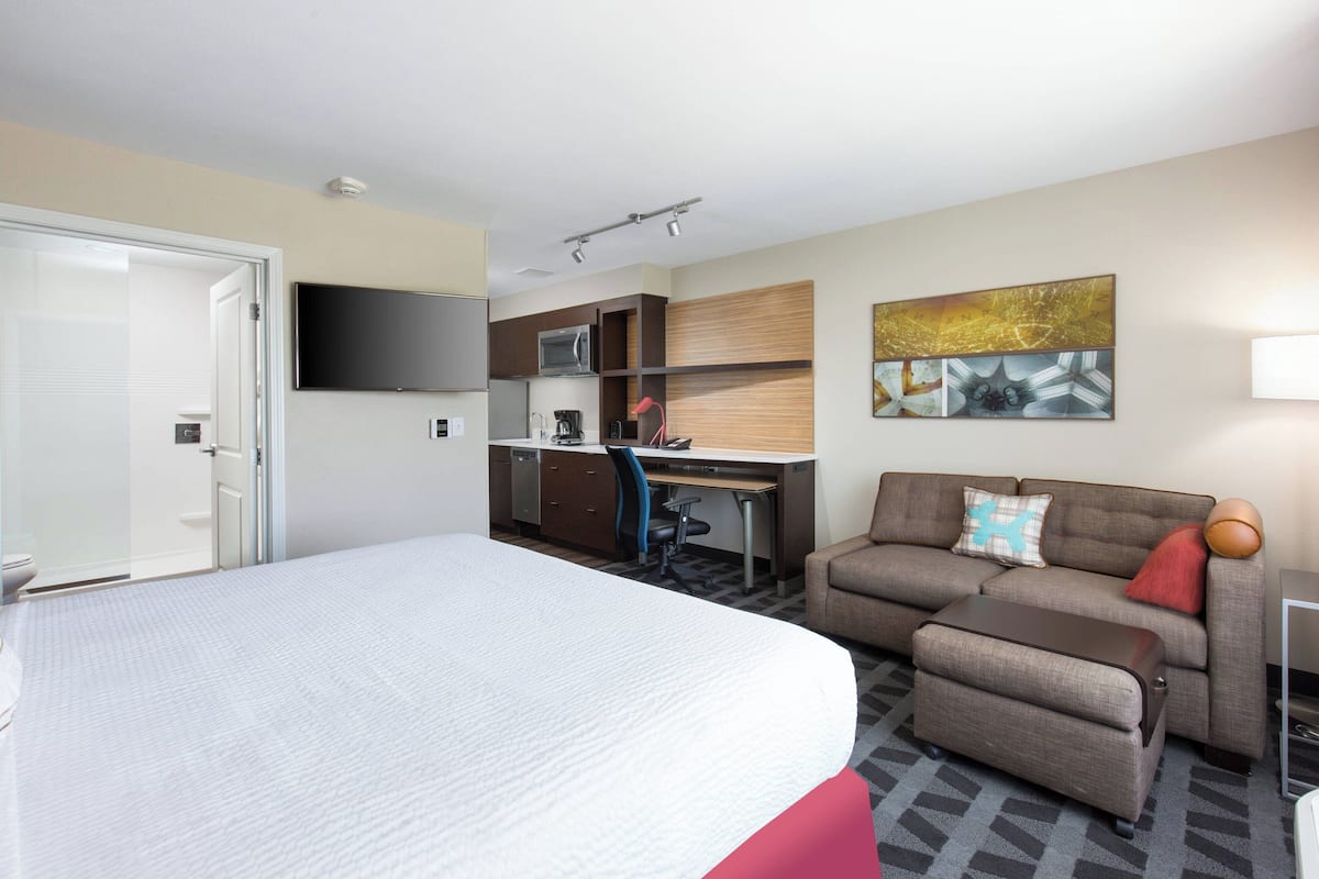 Una habitación de hotel con cama, escritorio, sofá, televisor y microondas.