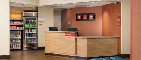 A reception area with a wooden reception desk, a seating area, and vending machines.