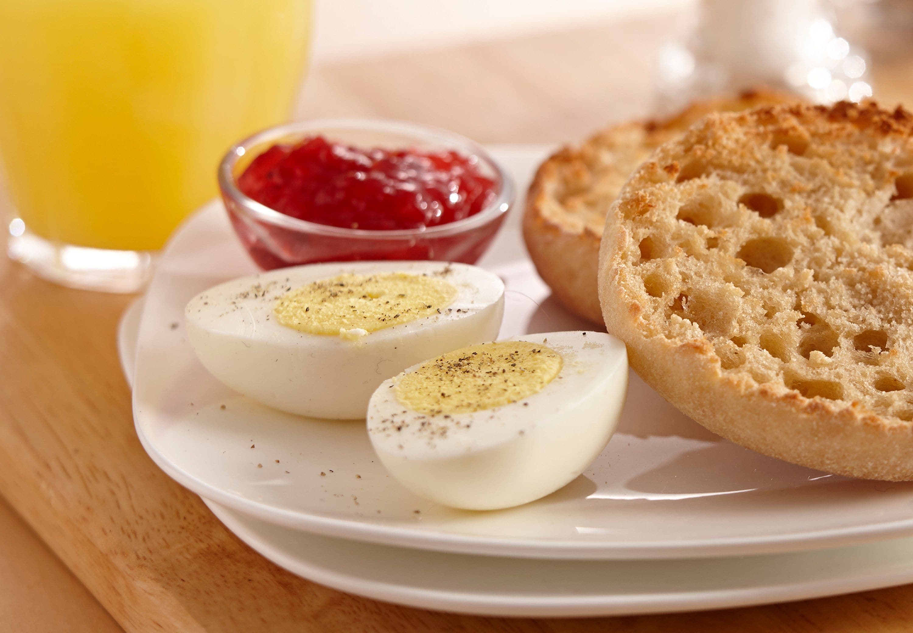 A plate with boiled eggs, toast, and jam.