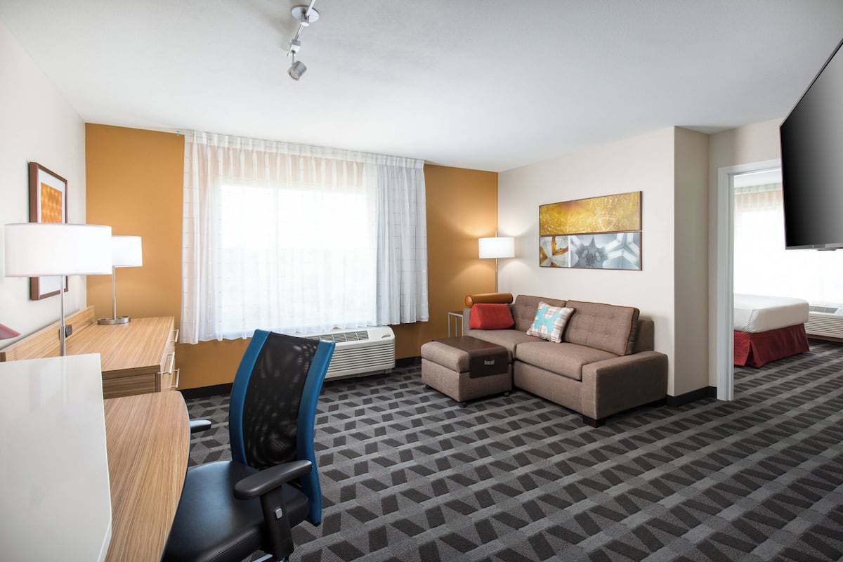 Una habitación de hotel con escritorio, silla, sofá y televisor.