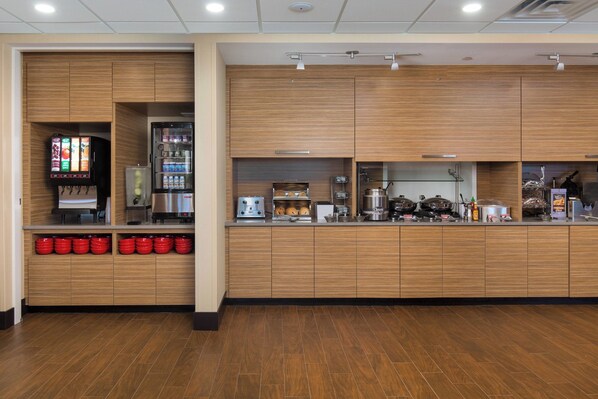 A modern kitchen area with wooden cabinets, a coffee machine, and a beverage dispenser. - TownePlace Suites by Marriott Austin North/Lakeline (Austin)