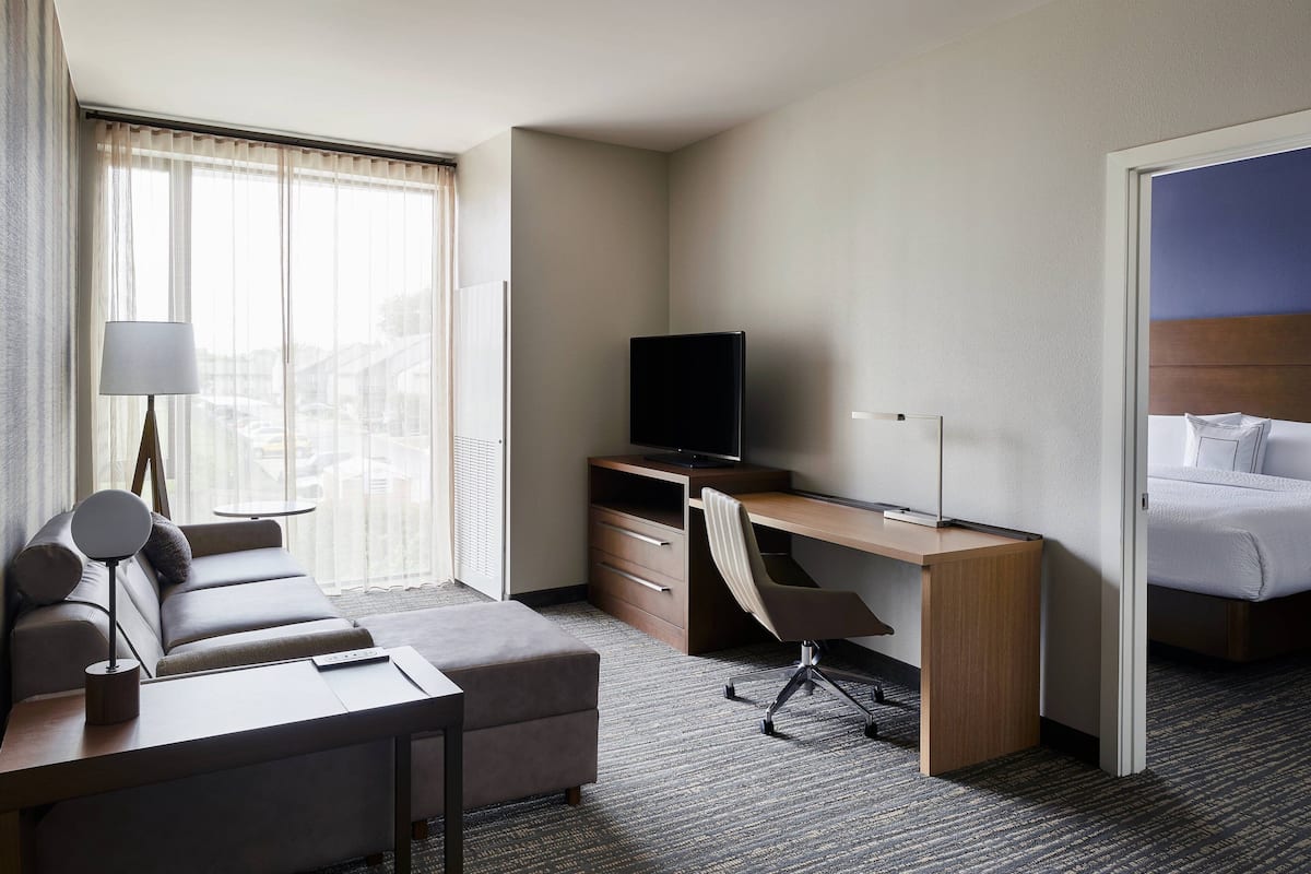 Une chambre d’hôtel avec un canapé, un bureau avec un ordinateur, une télévision et un lit.