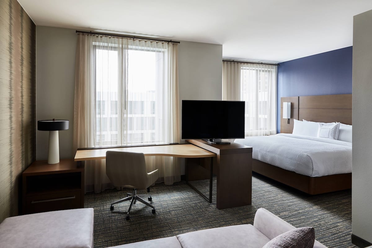 Une chambre d’hôtel comprenant un lit, un bureau avec un ordinateur et une télévision, une chaise et un canapé.