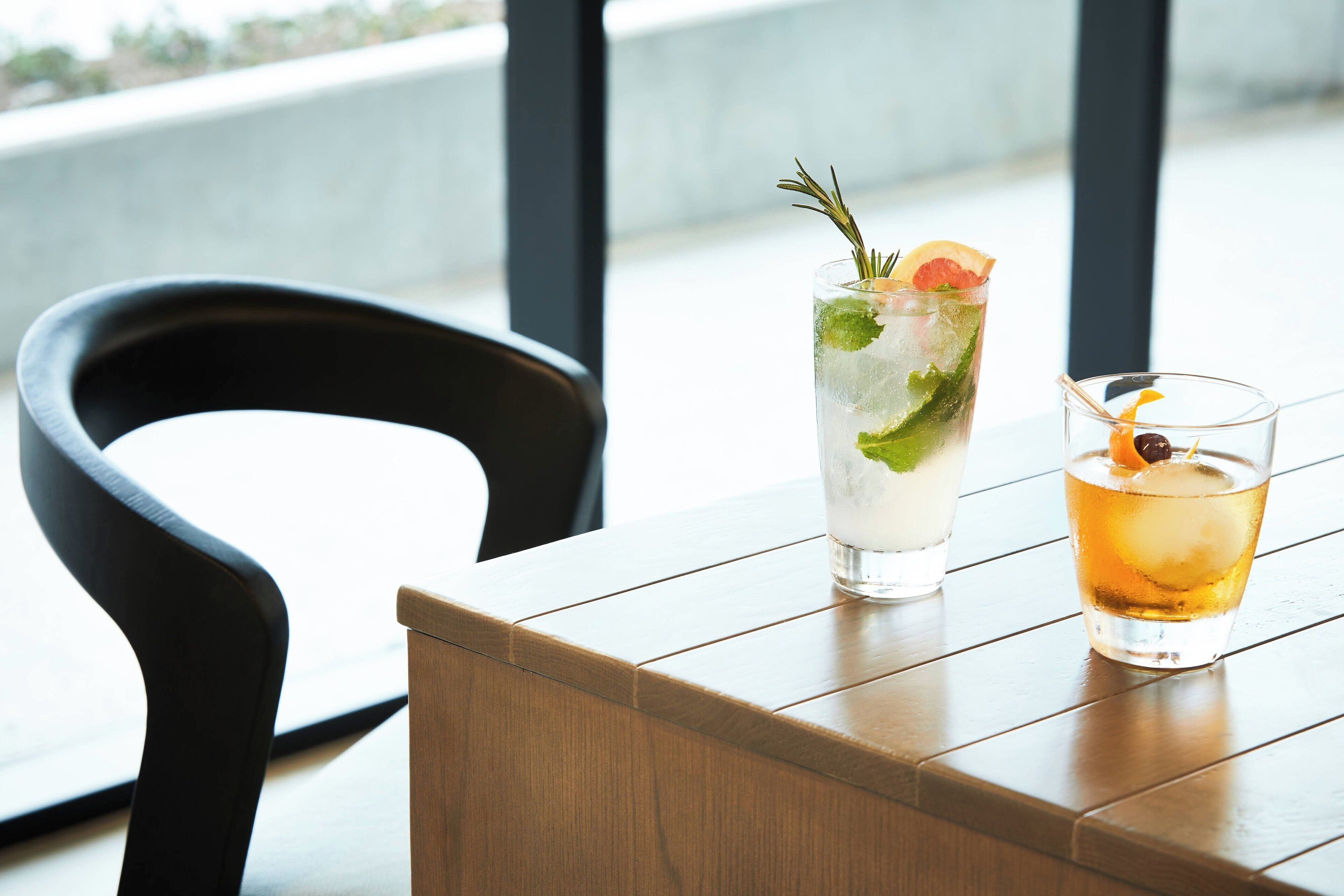 Deux boissons sur une table en bois, avec une chaise noire au premier plan.