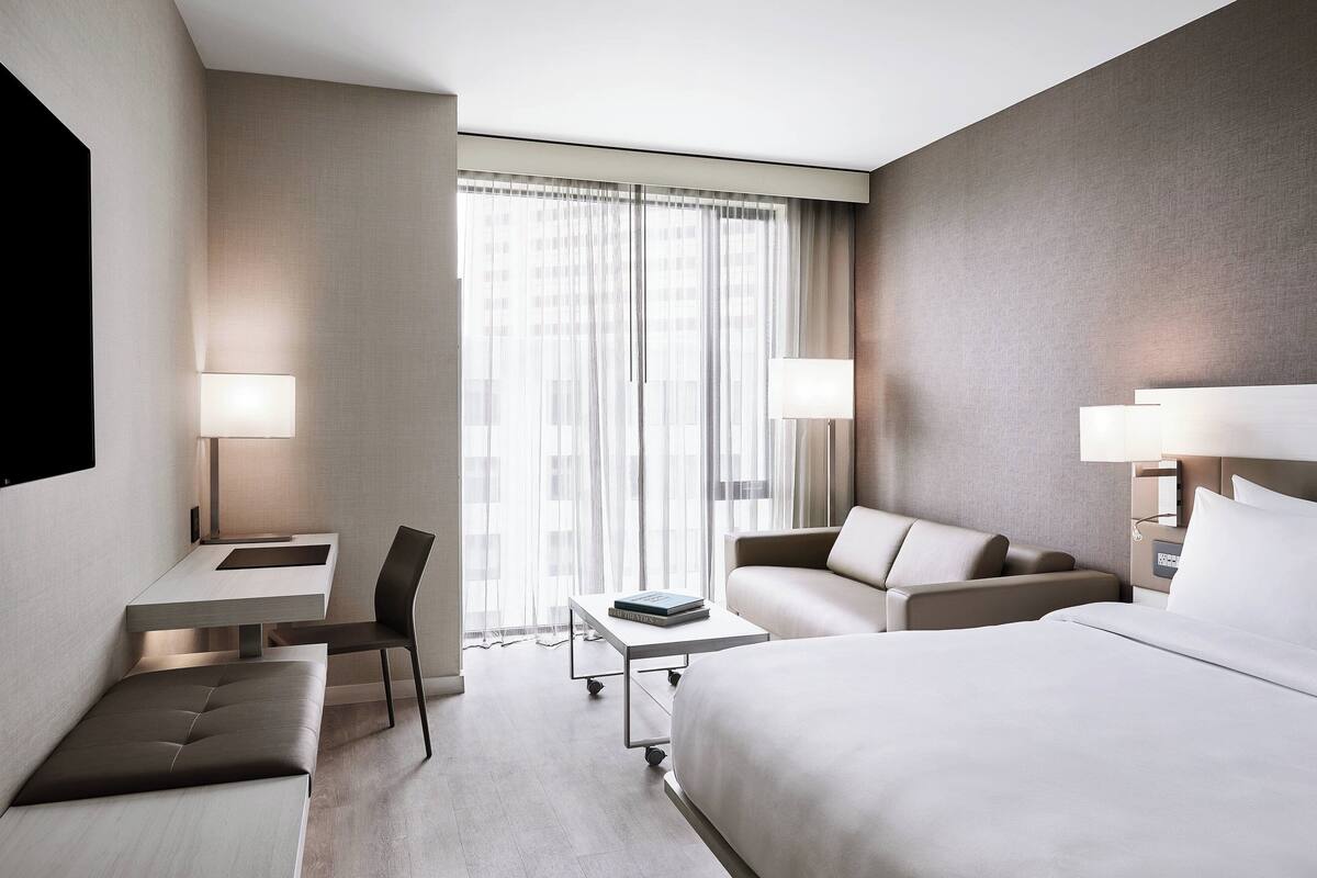 Een moderne hotelkamer met een bed, een bureau, een stoel en een bank.