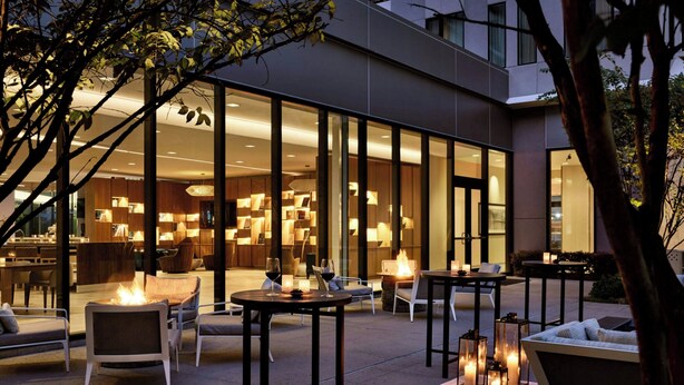 An outdoor patio area with seating, tables, and ambient lighting. - AC Hotel by Marriott Dallas by the Galleria (Dallas)