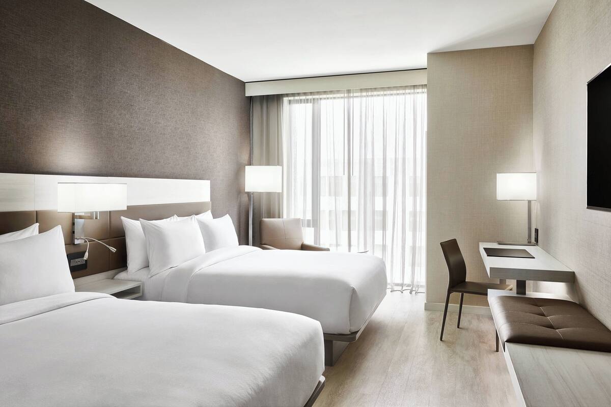 Een hotelkamer met twee bedden, een bureau en een stoel.