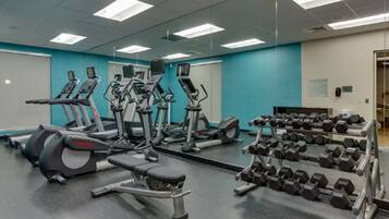 Ein Fitnessstudio mit Laufbändern, Crosstrainern und einer Hantelbank.