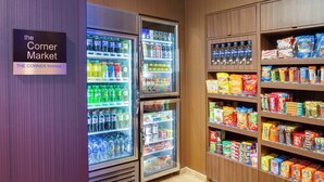 Een buurtwinkel met gekoelde drankautomaten en schappen vol snacks en dranken.