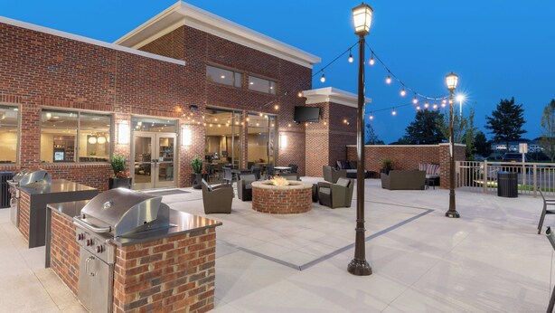 An outdoor patio with a brick fireplace, outdoor kitchen, and seating area. - Residence Inn by Marriott Greenville (Greenville)