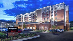 A multi-story hotel with a brick facade, multiple balconies, and a parking lot with several cars. - Residence Inn by Marriott Greenville (Greenville)