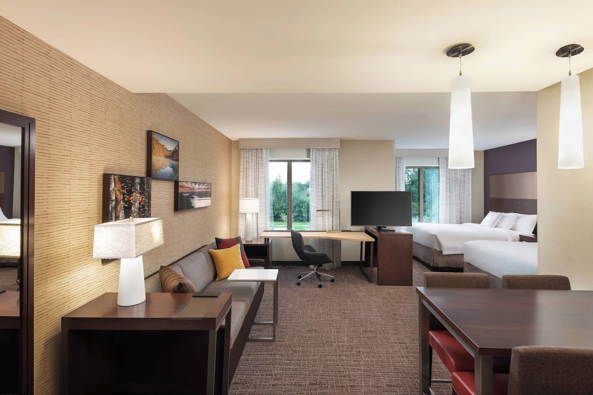 A hotel room with a bed, desk, chair, and a TV.