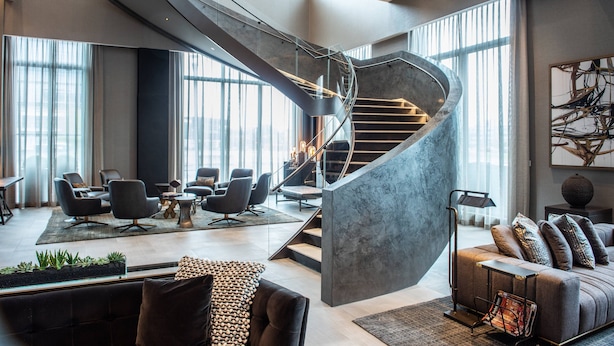 A modern interior with a spiral staircase, contemporary furniture, and large windows. - The Row Hotel at Assembly Row, Autograph Collection (Somerville)