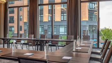A conference room with a long table, chairs, and a view of a brick building through large windows.
