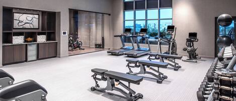 Un gimnasio moderno con cintas de correr, elípticas y pesas libres.